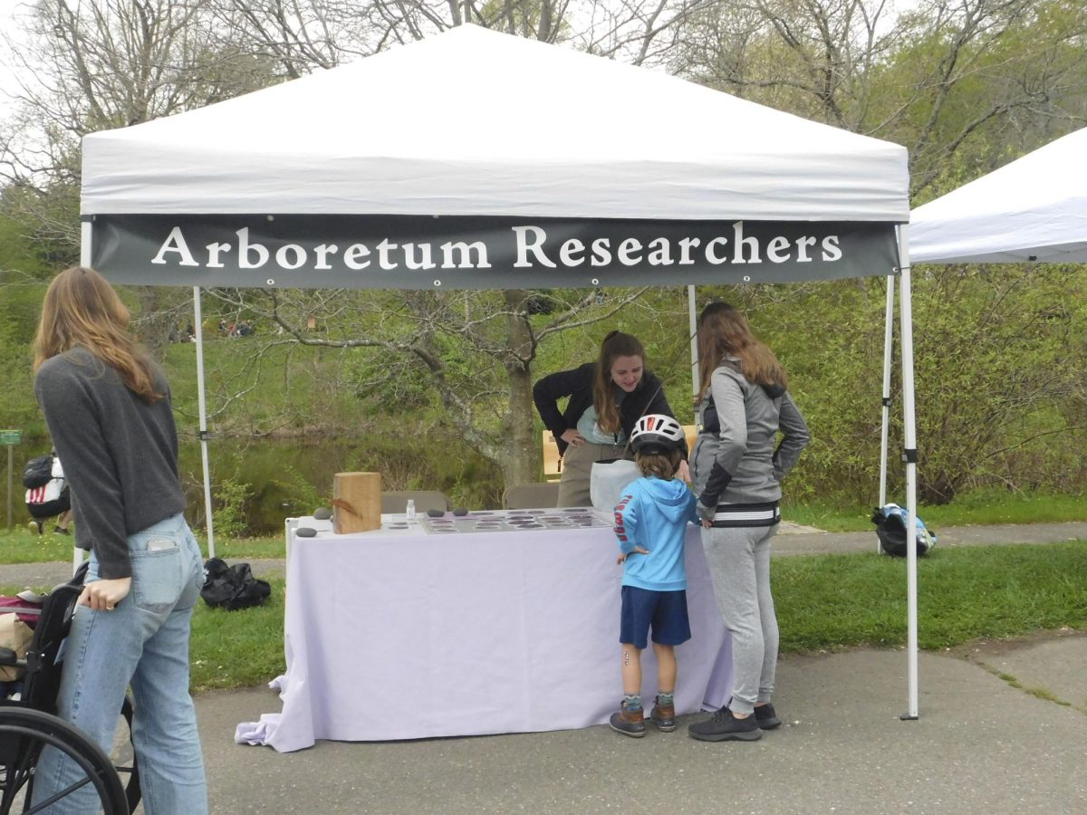 A volunteer shows a child and their mother a presentation about how trees work under stress at a tent labeled “Arboretum Researchers.” The station showed various research projects that are in-progress at the Arboretum.