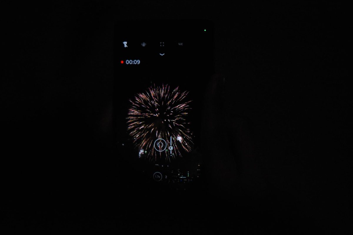 A spectator records a burst of colorful fireworks on their cell phone. Along with taking in all the sights with their eyes, many spectators also took pictures and videos of the show with their cell phones and cameras.