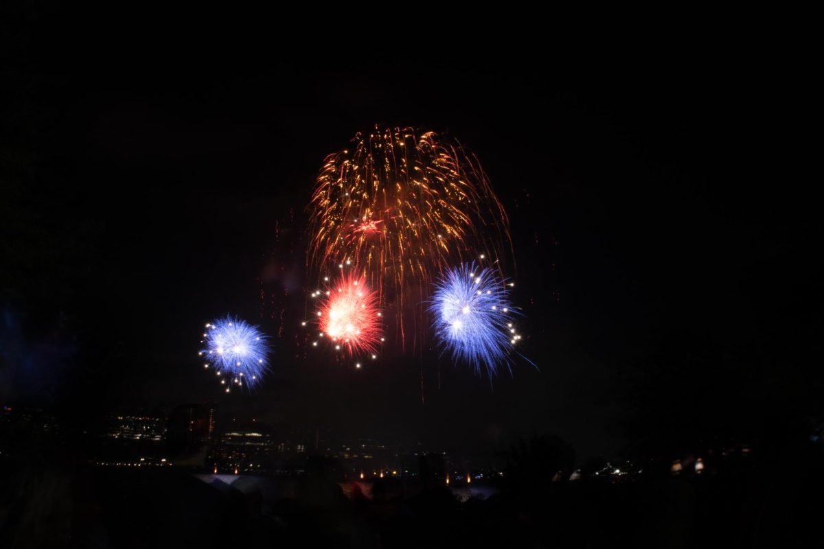 Red and blue fireworks burst below a golden brocade. Fireworks in patriotic colors were common during the display.
