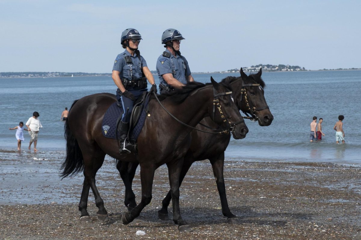 Two police officers ride horses on the beach. Participants happily watched the horses walk past the rides and vendors on Revere Beach Boulevard before moving onto the beach.