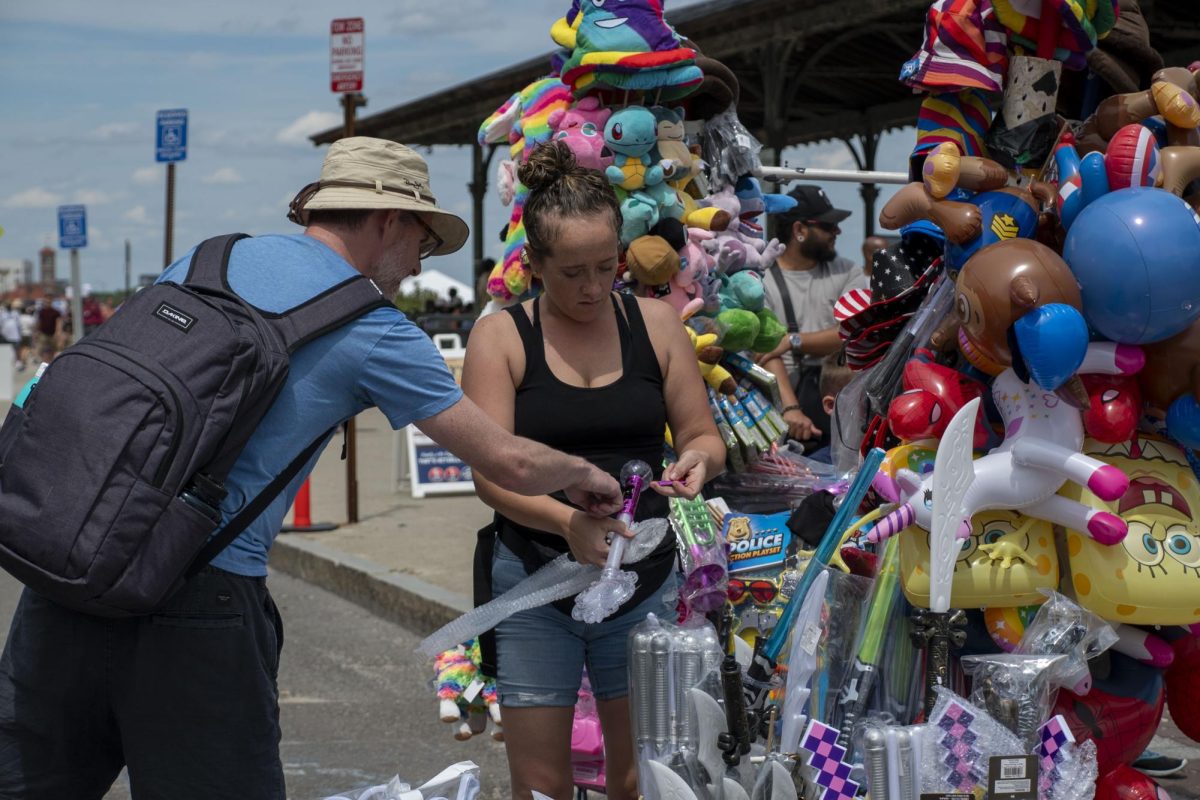 A vendor helps set up a light-up wand toy for a participant. Vendors also sold stuffed animals and balloons that resembled well-known cartoon characters.