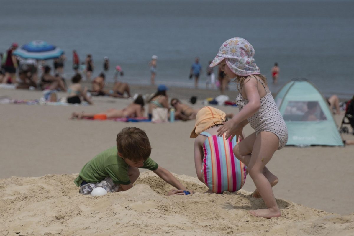 Three children play in the sand. Despite the high temperatures and hot sand, the ocean water was cold, deterring many from swimming.