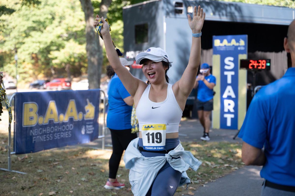 A runner raises her hands after crossing the finish line.