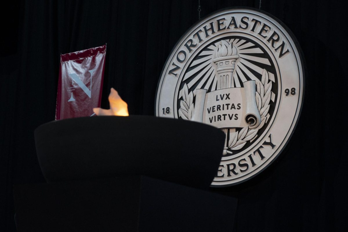 A Northeastern University seal hangs behind a lit ceremonial torch at the 2024 convocation ceremony in Boston. Demographic data published Thursday morning by Northeastern Global News revealed that 5.1% of students in the class of 2028 identify as Black, as compared to 7.8% of students in the class of 2027.