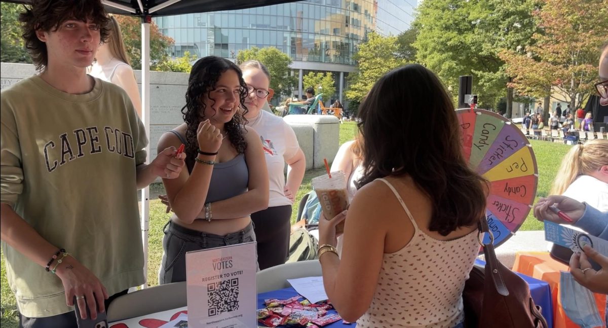 Students spin a prize wheel at the Northeastern Votes table in Centennial Common. The organization gave out stickers, pens and candy to celebrate National Voter Registration Day.