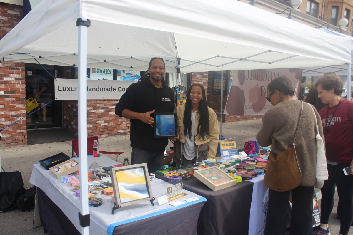 Rahim Gray poses with one of his acrylic pour art pieces. Gray makes and teaches pour art with acrylics on coasters and canvas pieces.