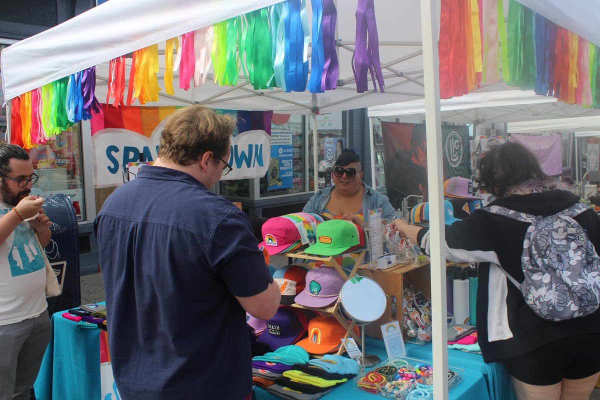 Attendees look at hats and stickers while speaking to Robyn Giragosian. Their business, Sparkletown Studios, had popups all around Boston.