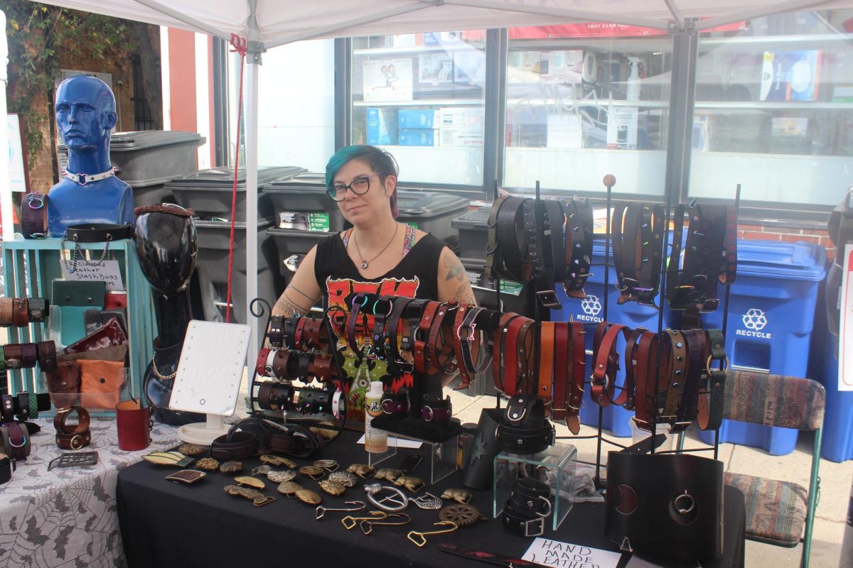 A vendor sits with their handmade leatherwork. Leather was commonly-sold merchandise among businesses throughout the event.