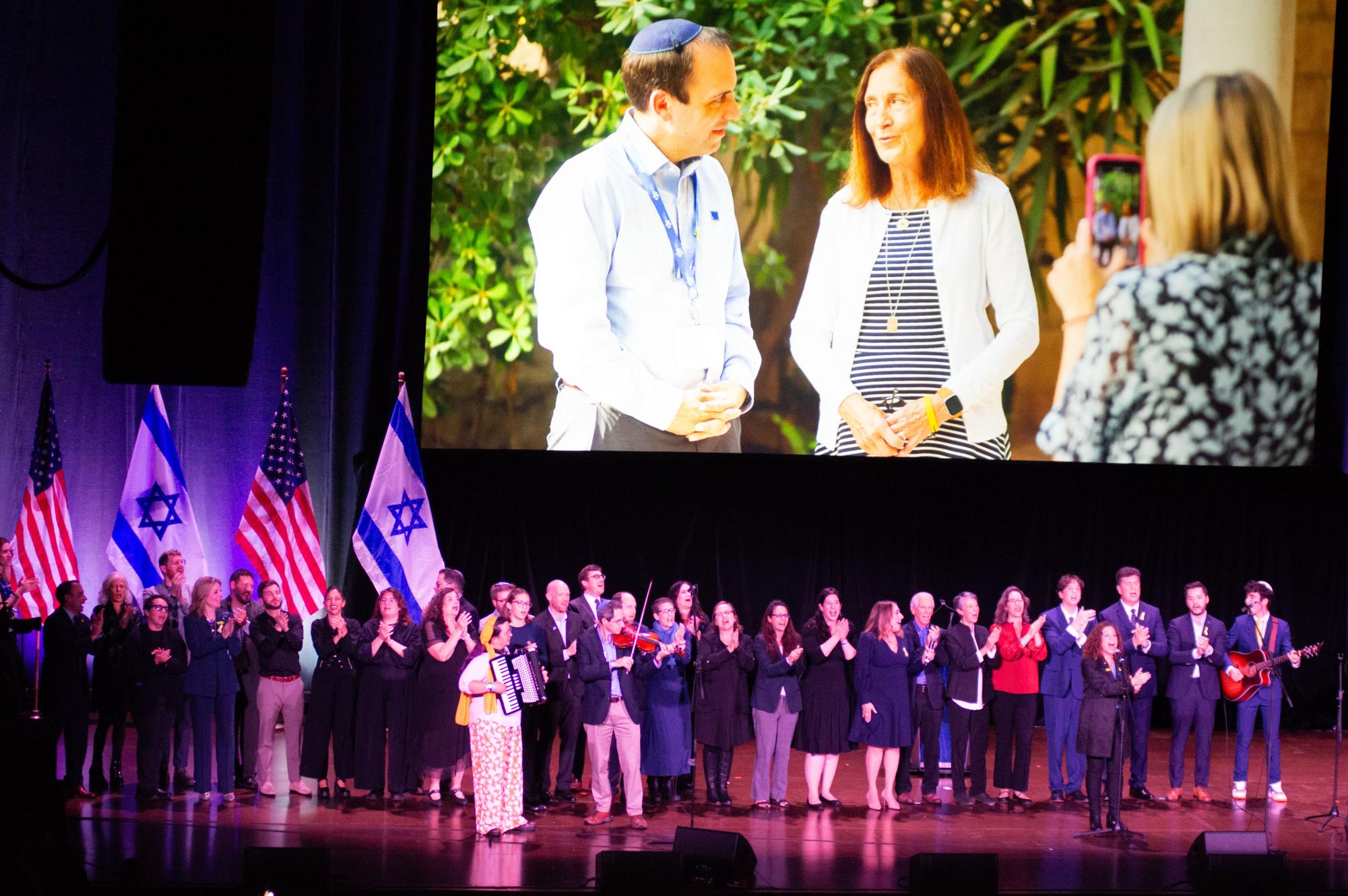 A group serenades the audience as a slideshow of images plays in the background. Songs and the prayer Oseh Shalom ended the ceremony.