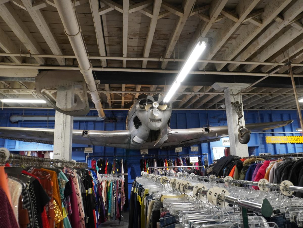 An old plane protrudes out of the wall over racks of clothing. The building dates back to 1893, where it was once a soap factory, Cambridge Printing Company, a bronze foundry and Harbor Textile Waste Company.