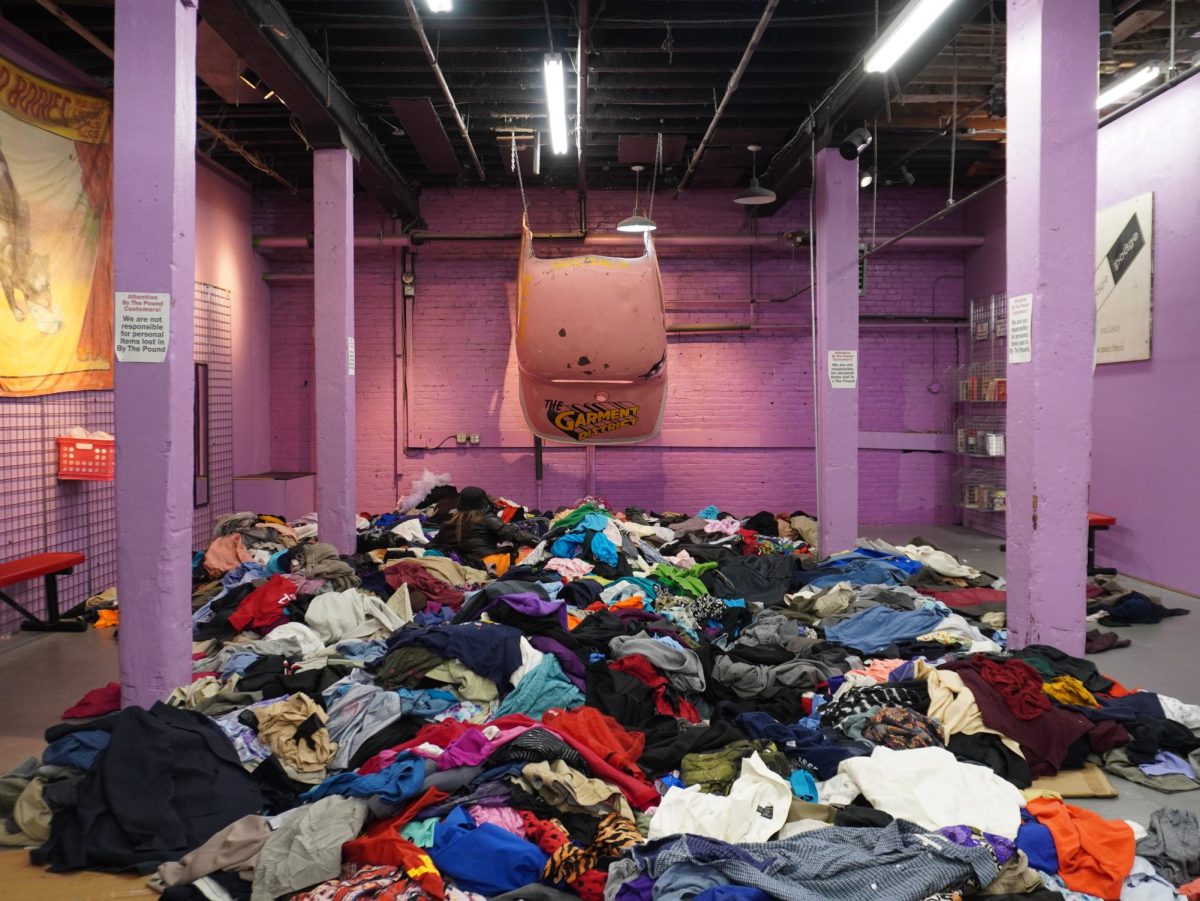 Piles of clothes sit strewn about on the floor. Many customers sat on the floor sifting through the massive piles.