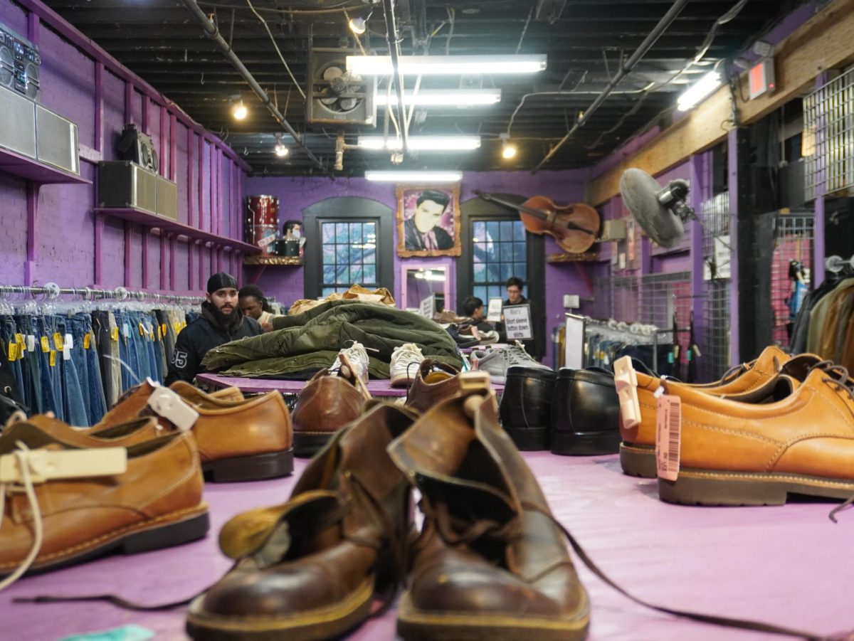 Shoes sit on top of a rack of clothes, with drums, a bass and an Elvis Presley picture displayed on the walls in the background. Many customers arrived with groups of friends to shop.