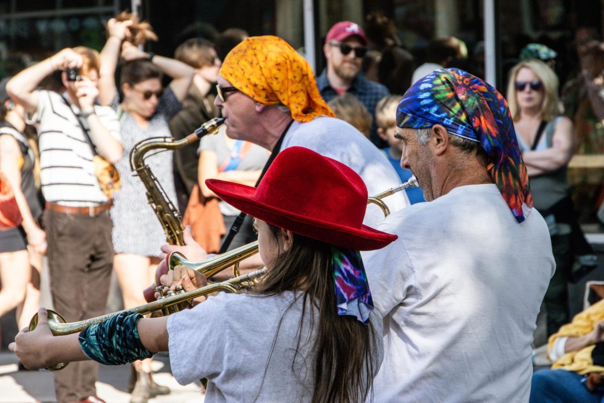 Three musicians in a brass section play in front of J.P. Licks. Most bands had a diverse mix of players of all ages ranging from young teens to elderly performers.