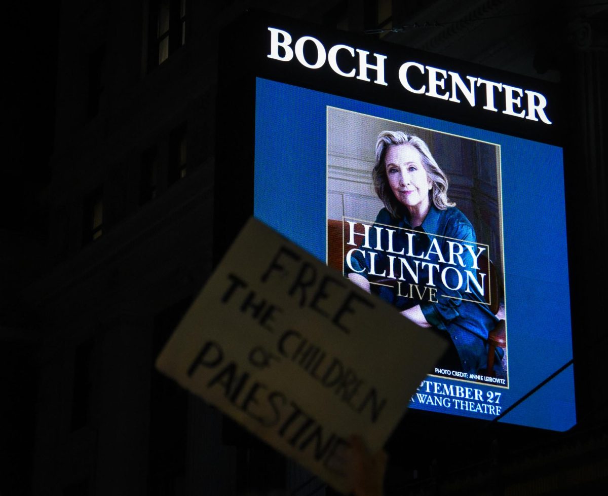 The Boch Center display outside the Wang Theatre spotlights an ad for Clinton’s speaker event as a protester holds up a sign that reads, “Free the children of Palestine.” Protesters carried signs of all shapes and sizes with various messages related to the Israel-Hamas war.