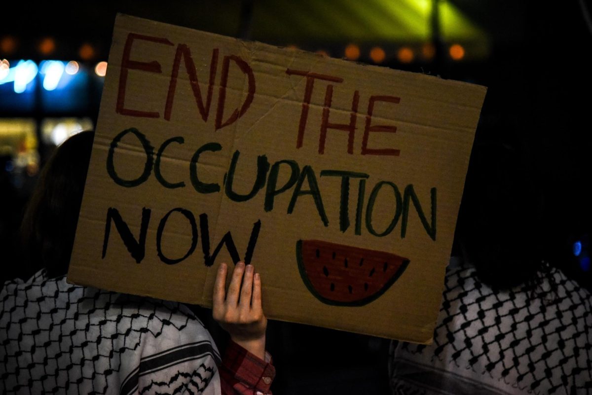 A picket member holds up a sign as the marching portion of the protest pauses in front of the Wang Theatre. Organizers not only used megaphones to voice their protest efforts, but also to speak to and direct the picket.