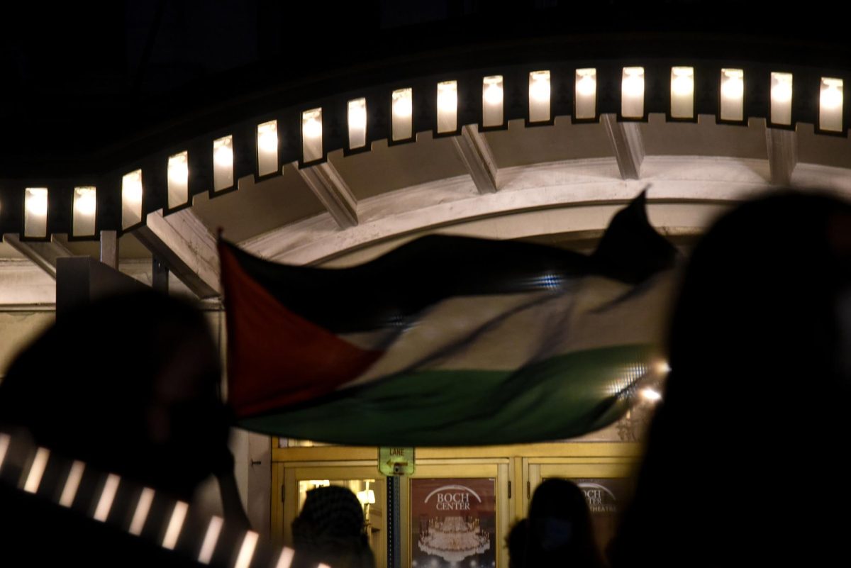 A protester waves a Palestinian flag while walking in front of the Wang Theatre as Clinton’s event begins. The picket stayed active in front of the theater even after all of the patrons were inside and the doors to the event closed.