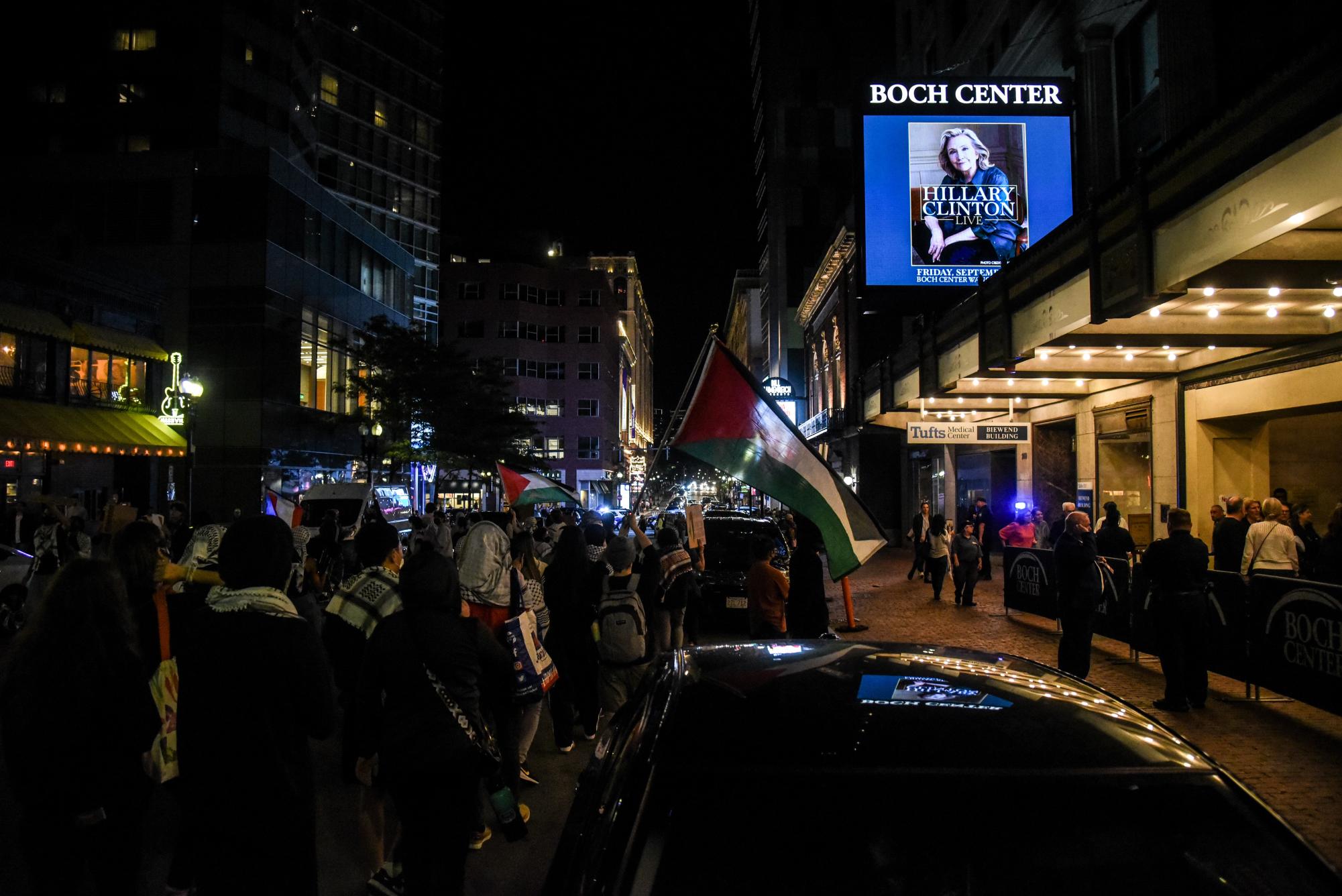 Demonstrators march directly outside the Boch Center as the last of Clinton’s audience members enter the theater for her show. The group marched in a circle on the street in front of the theater.