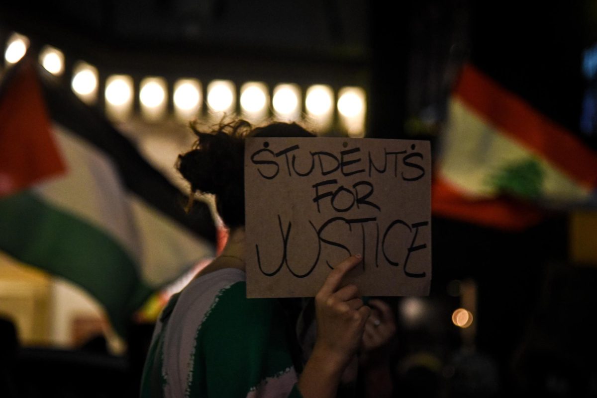 A picketer shields their face with a sign while marching. While the protest consisted of multiple organizations, some of the group contained students from nearby colleges like Suffolk University and Emerson College.