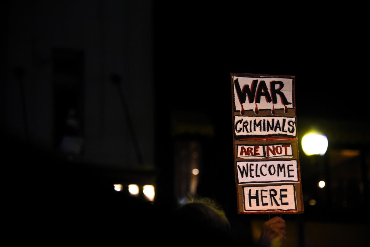 A demonstrator raises a provocative sign in the air. Picketers held signs taking various jabs at Clinton, labeling her a war criminal.