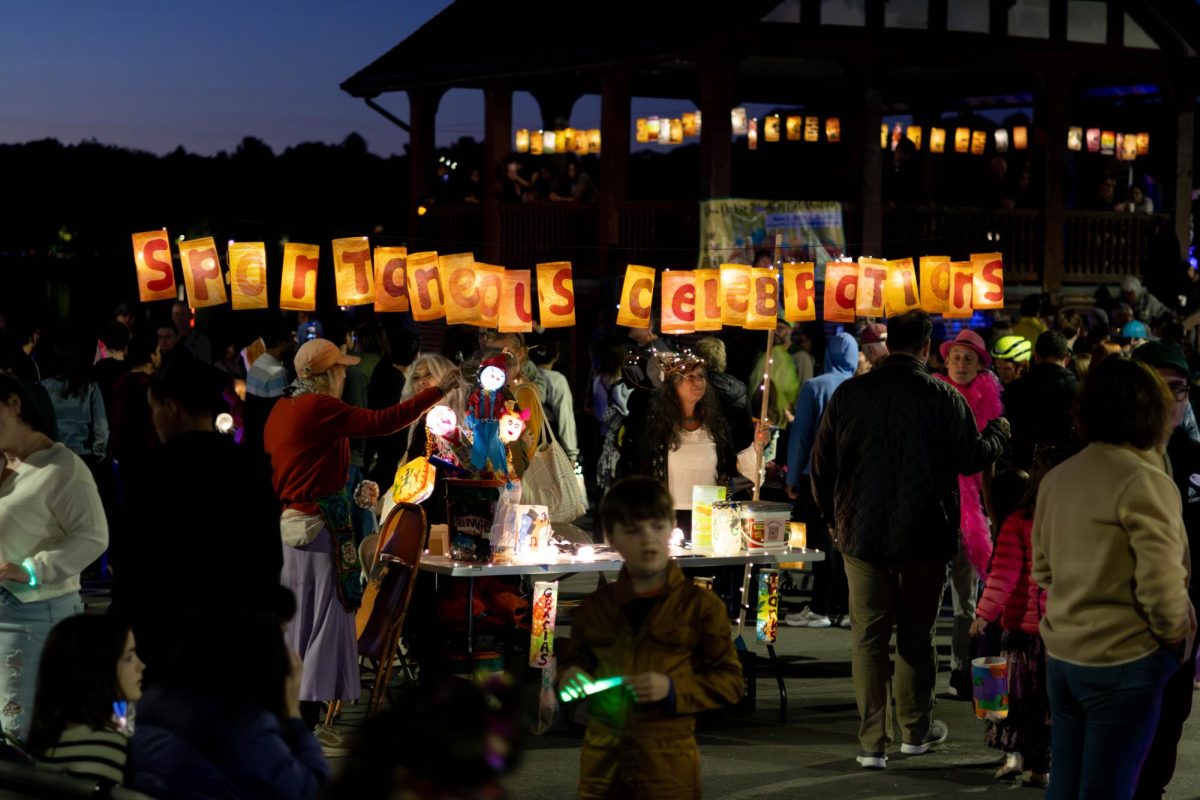 Festival goers approach the welcome table decorated with paper lanterns and lights. Spontaneous Celebrations ensured a fun, lively atmosphere by incorporating parades, live music and food.