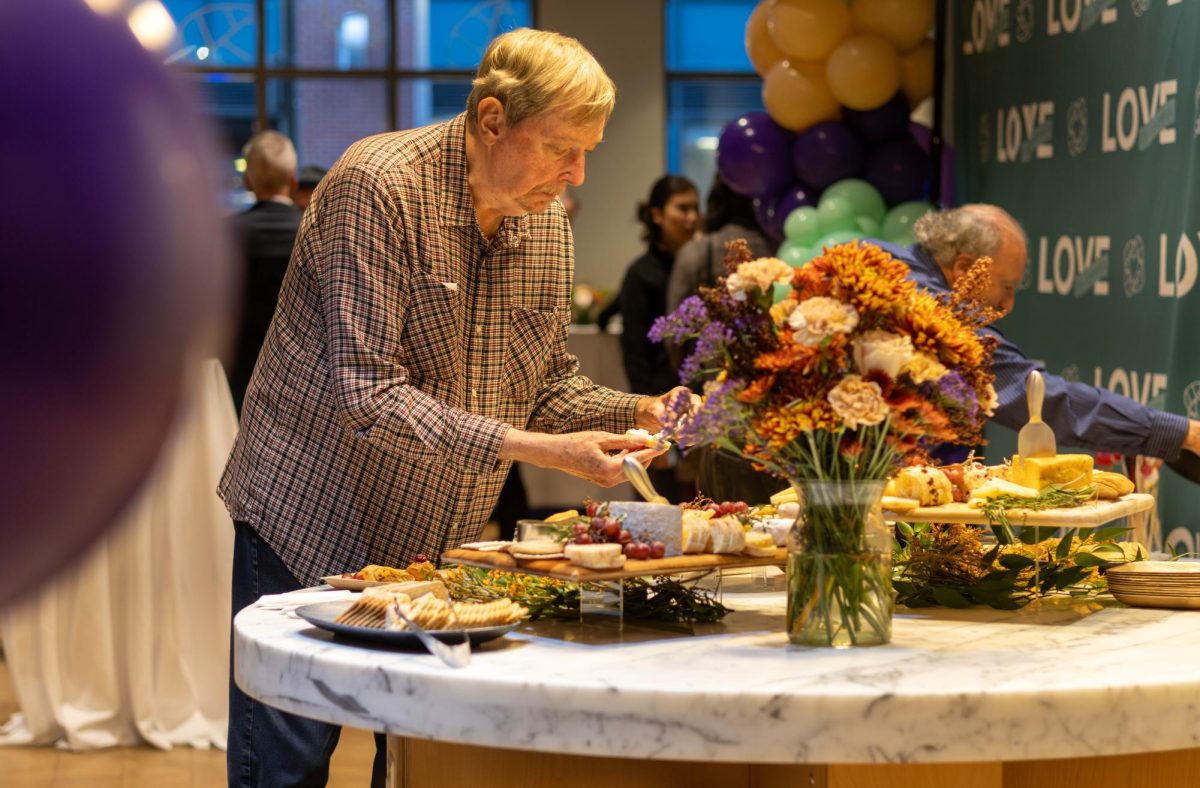 A Love The Fenway fundraiser attendee places a various cheese, crackers and grapes onto his plate. The fundraiser offered an open bar, a charcuterie table and numerous hors d'oeuvres.