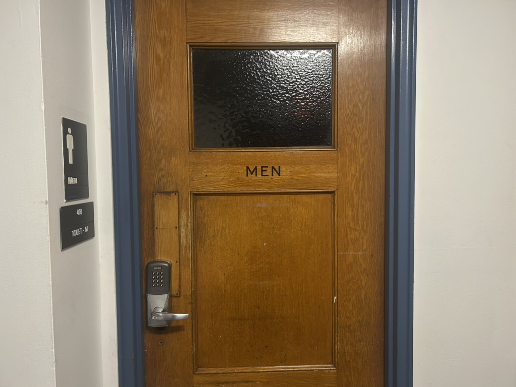 The entrance to a men’s bathroom in Mugar Hall. NUPD implemented locks on some of Mugar Hall’s bathrooms in response to illegal activity, which was later confirmed to be in relation to prostitution.