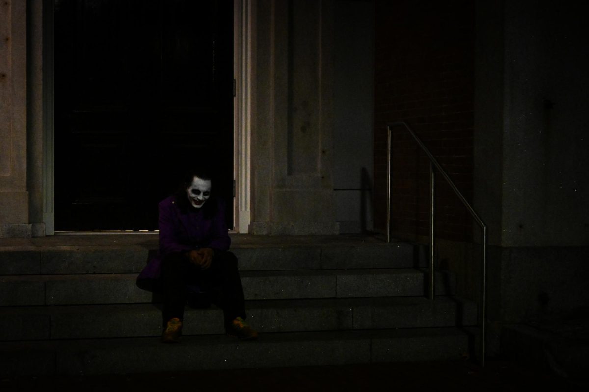 As nighttime approaches, a costumed Joker gives an eerie smile and stares as they sit on the steps of a building along Essex Street. The sun setting didn’t deter performers and those in costumes, as they still roamed the area interacting with onlookers as the night progressed.