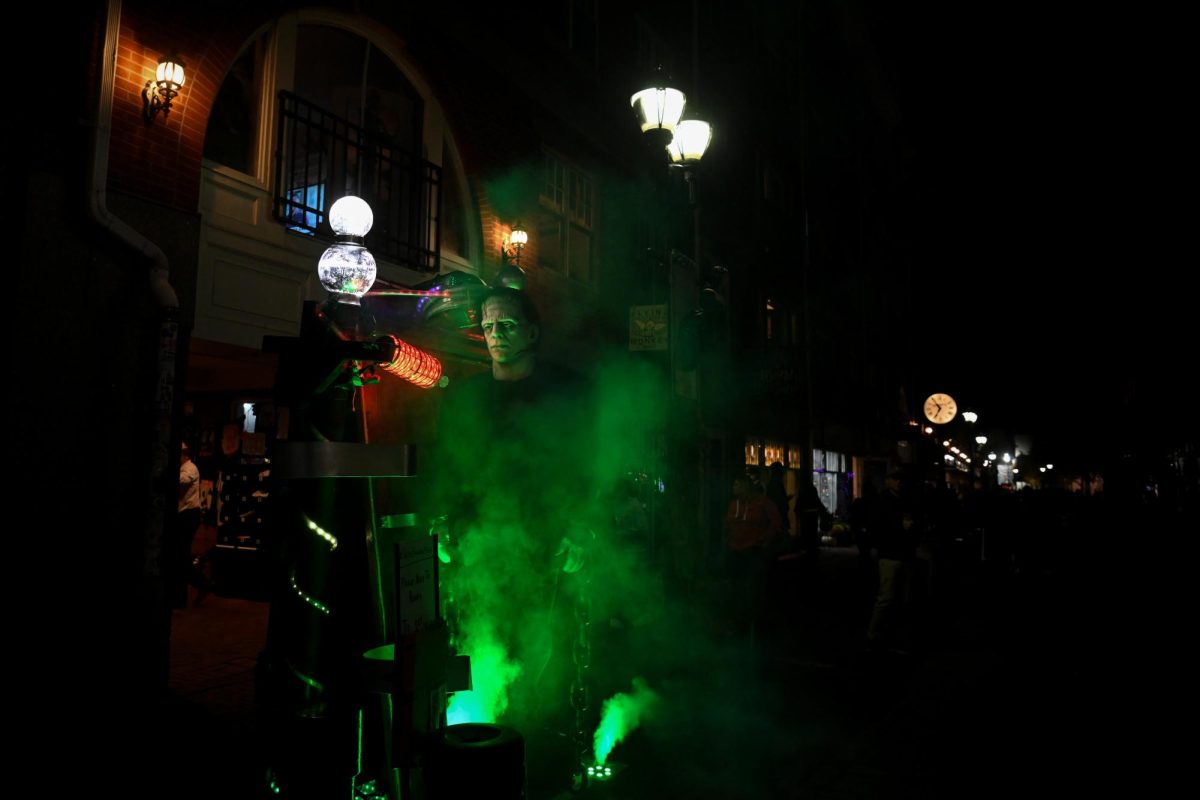 A Frankenstein performer stands on a decorated laboratory-esque platform blowing colorful smoke. The daytime festivities extended to nighttime as Salem continued to come alive with costumes, live music and entertainment.