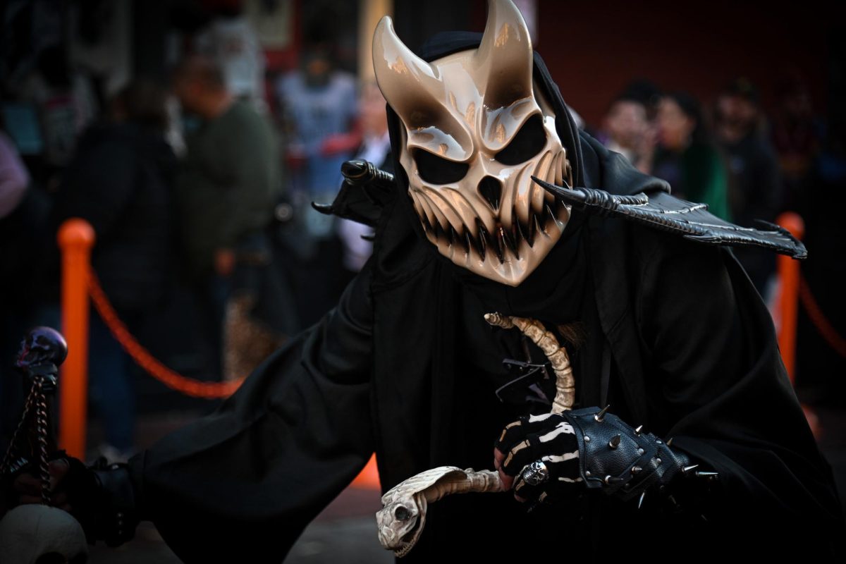 A costumed individual showcasing an eerie mask stares as they glide through the Haunted Happenings marketplace. While some dressed up for tips, others just passed through the crowds showcasing their costumes and spooky adornments.