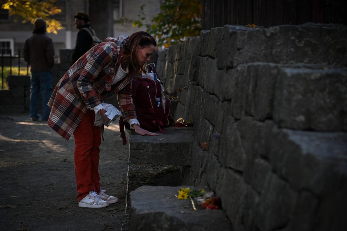 An individual pays their respects at a stone bench for a Salem witch trials victim at the Witch Trials Memorial Site in Downtown Salem. The trials began in 1692 and took the lives of 25 innocent individuals, of which many are honored at the memorial.