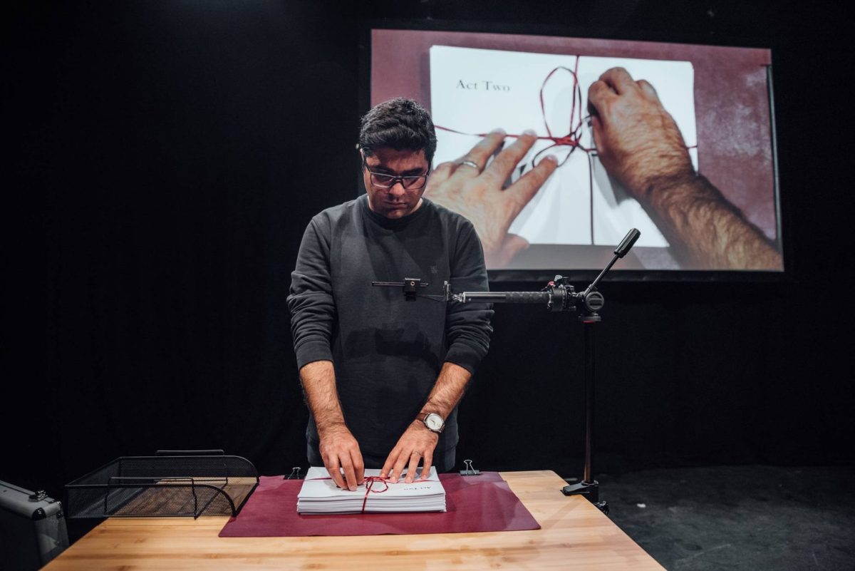 Nassim Soleimanpur unties the string binding the Act Two script together. Guest performers went in blind, unaware of the script contents until they stepped onstage. Photo courtesy David Monteith-Hodge.