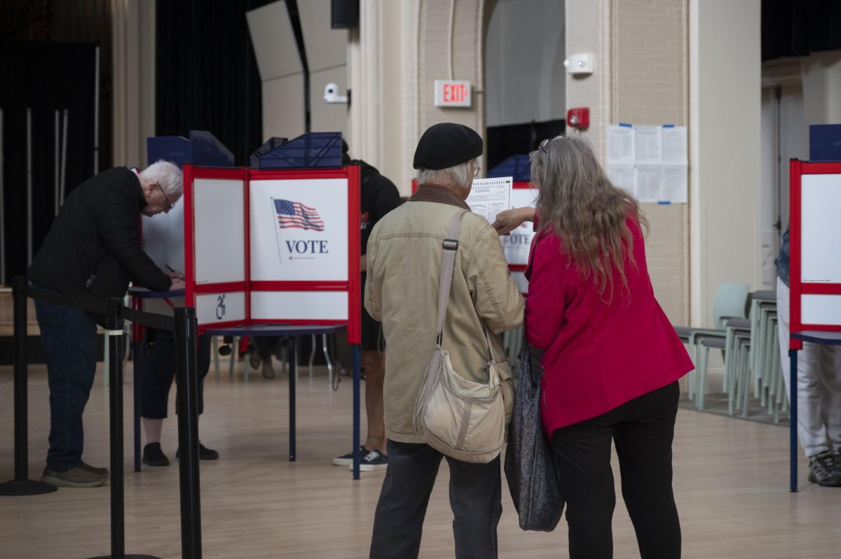 Two voters discuss the ballot before voting at the Fenway Center. Voting centers emphasized that the Massachusetts ballots featured ballot measures and Senate candidates in addition to those for the presidency. 