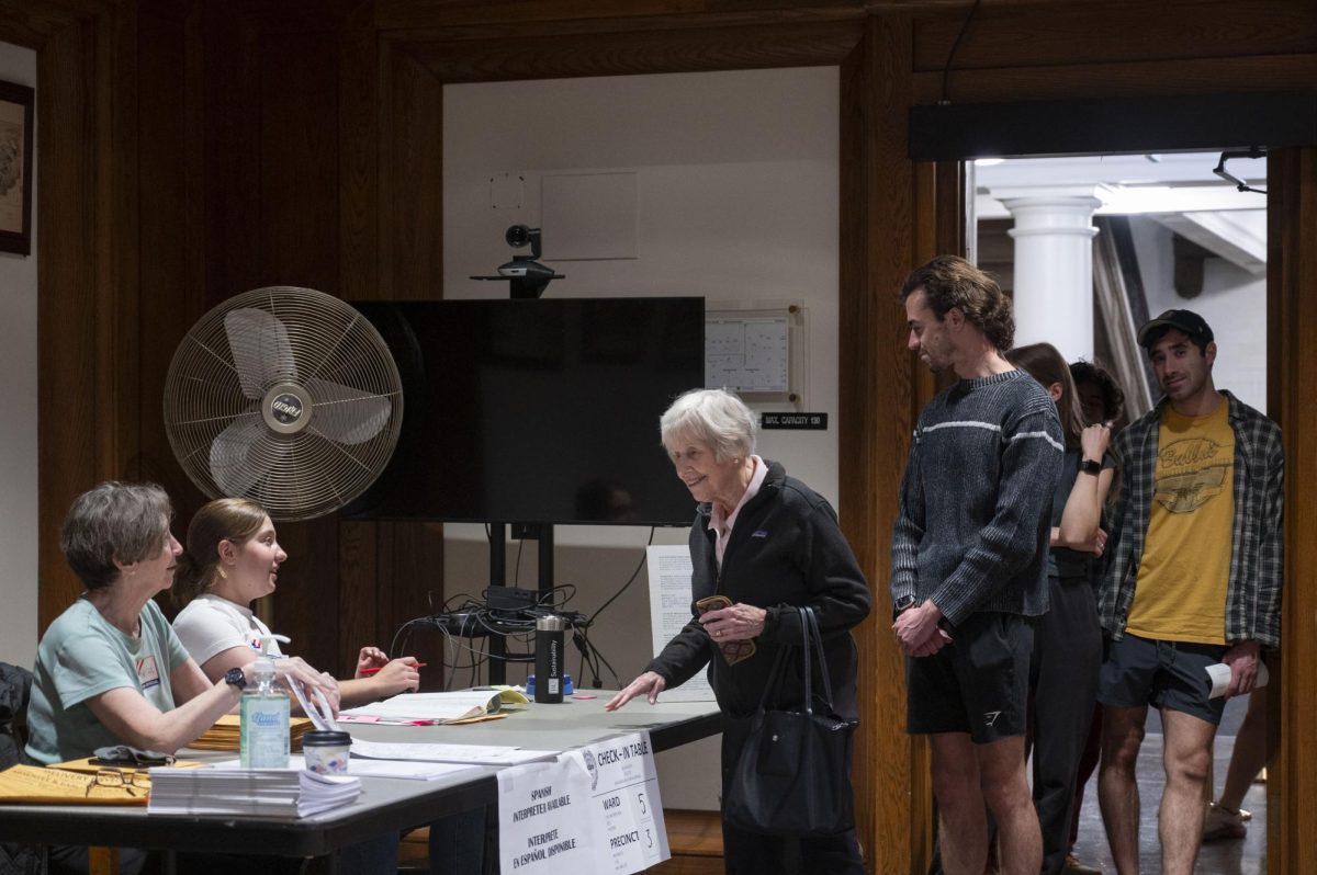 A voter smiles while checking in to vote at the State House. Informational pamphlets and signs were provided in different languages at all polling locations.