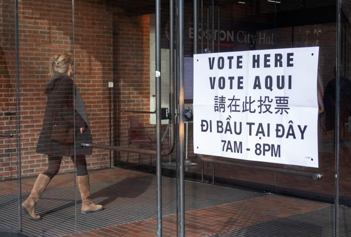 A woman enters City Hall, passing by voting signage. City Hall also had a ballot drop-off box outside.