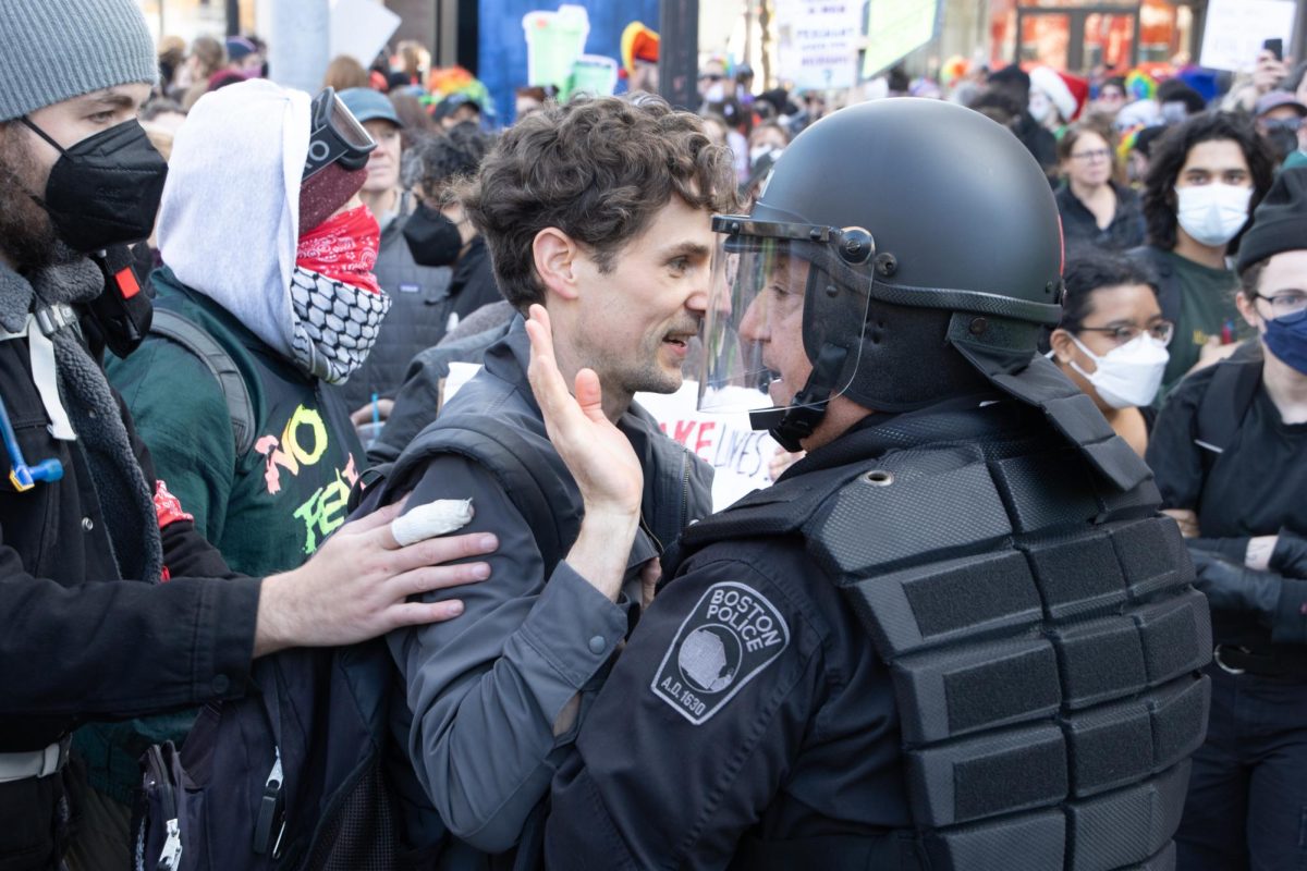 A counterprotester raises his hands as BPD officers in riot gear push the crowd back. Some pro-choice activists used civil disobedience tactics like kneeling or standing in front of the advancing police line, while others used bikes or a reinforced banner to push back against the police officers.