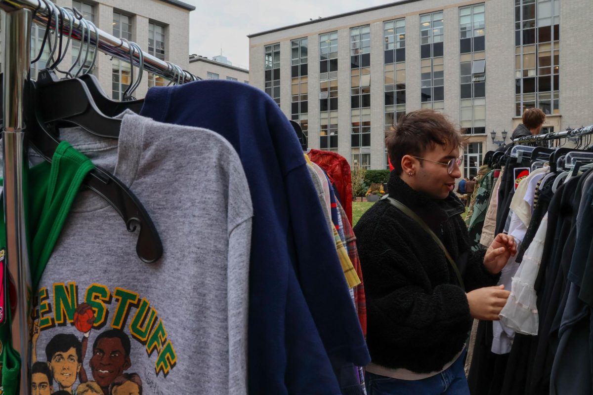 A student looks through a vendor’s clothing racks for potential items to purchase. Students enthusiastically approached various clothing racks as certain items caught their eyes.