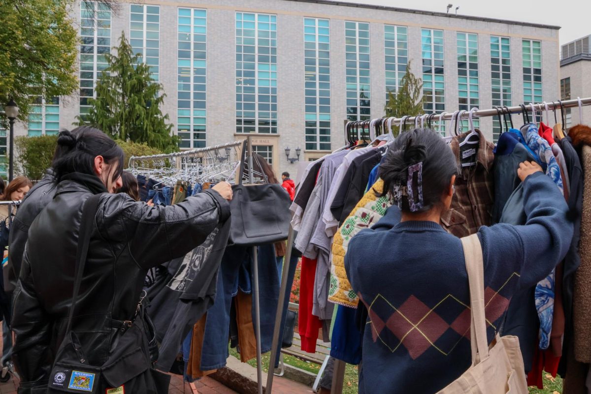 A student looks at a potential shirt to buy while another browses jackets. Students held up clothes for their friends’ judgments and debated purchasing items.