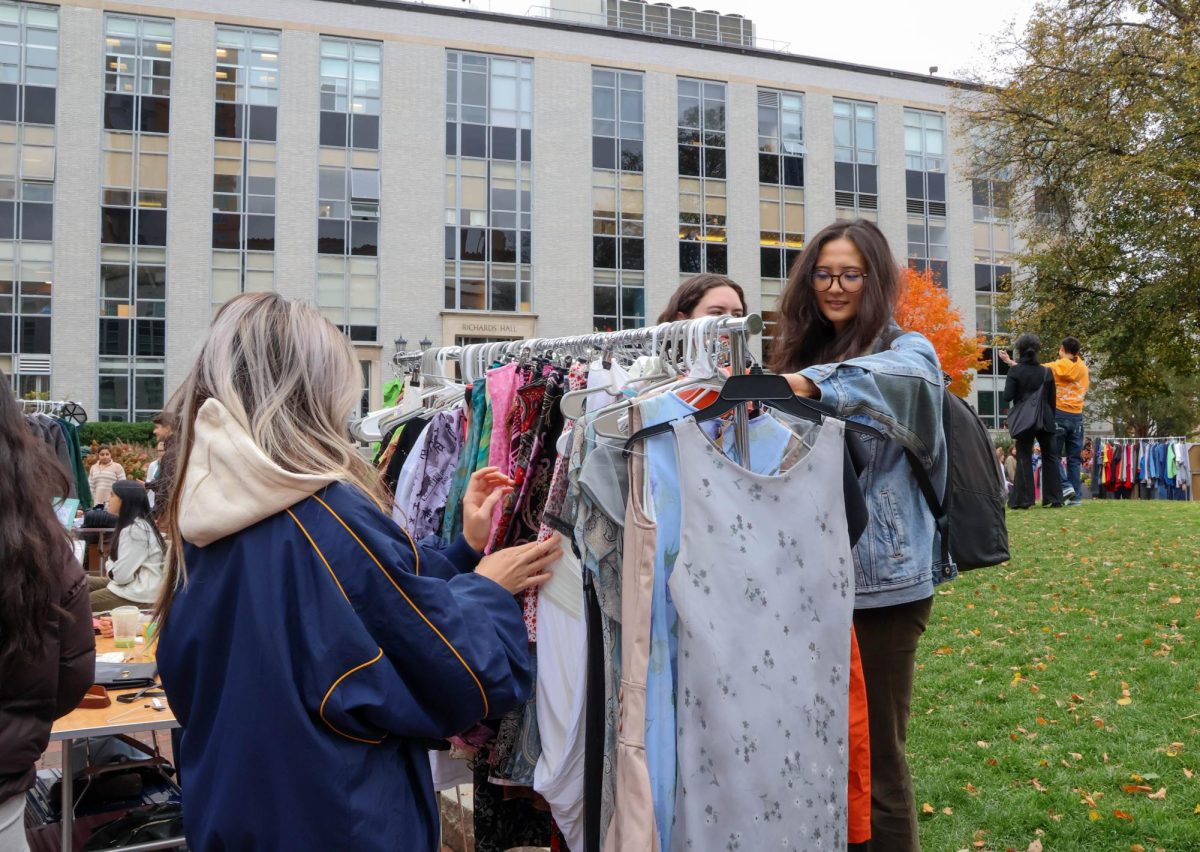 Northeastern students look through secondhand dresses. These items once belonged to the vendor and her friends who have curated their closets for the market.