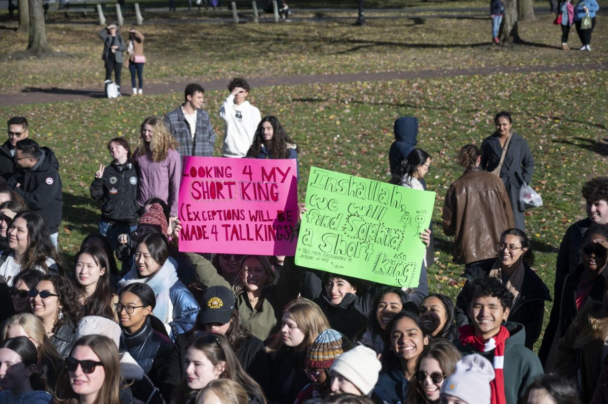 Two friends hold up neon handmade posters to advertise that they are looking for a “short king.” The crowd cheered more for contestants who said they were single.