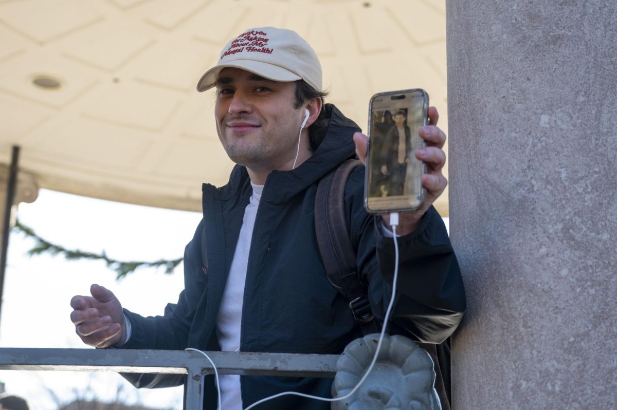 A contestant smiles while presenting a photo of Holland on his phone. The contestant intentionally wore wired earbuds to emulate a photo of Holland dressed similarly during the filming of “Spider-Man: Homecoming.”