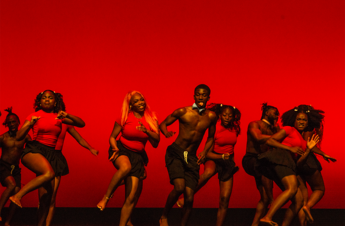 NASO’s dance team dances with a leg raised in red tops and black bottoms in front of a vivid red background. They were fourth to perform their enchanting routine.