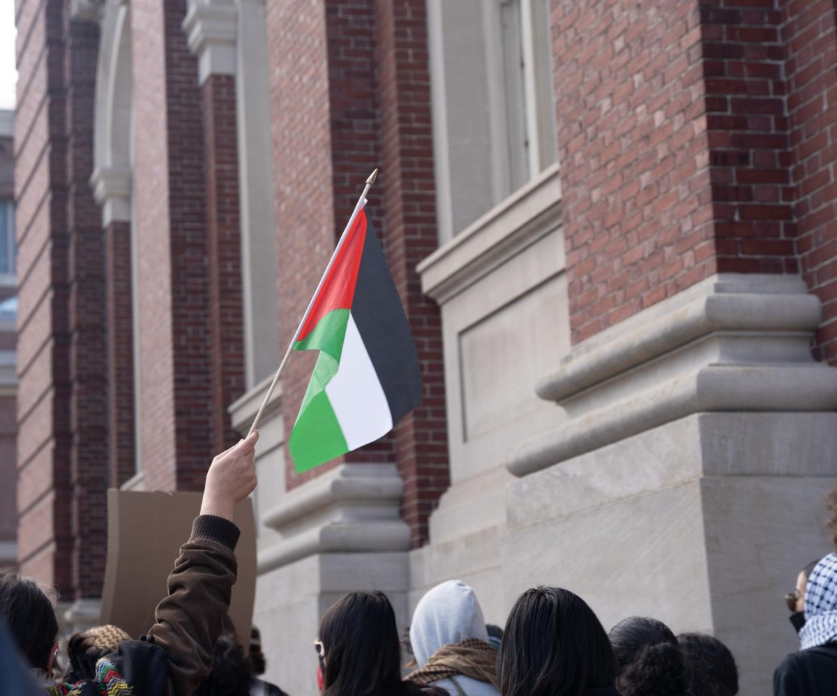 A protester holds a Palestinian flag up. NUSLSJP accused the Deans of the Law School of censorship via a letter shared on Instagram Dec. 3.