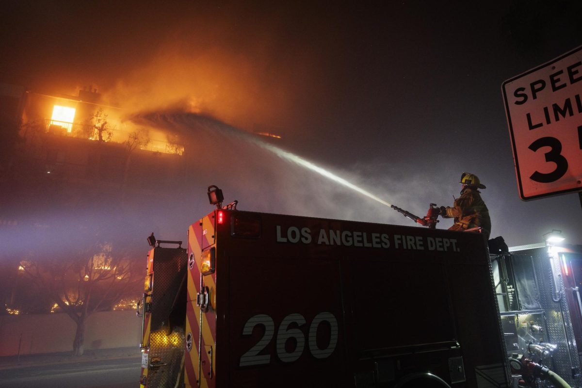 A firefighter sprays a burning building with water. Multiple wildfires had broken out in Los Angeles County, destroying thousands of buildings and resulting in thousands evacuating. Photo courtesy Caylo Seals.