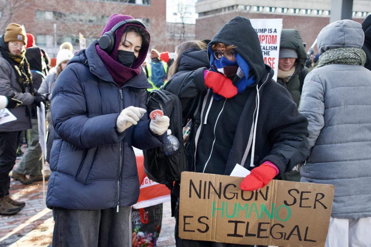 A protester hands another protester a button. There was various paraphernalia at the rally including stickers, flags and brochures for the public.