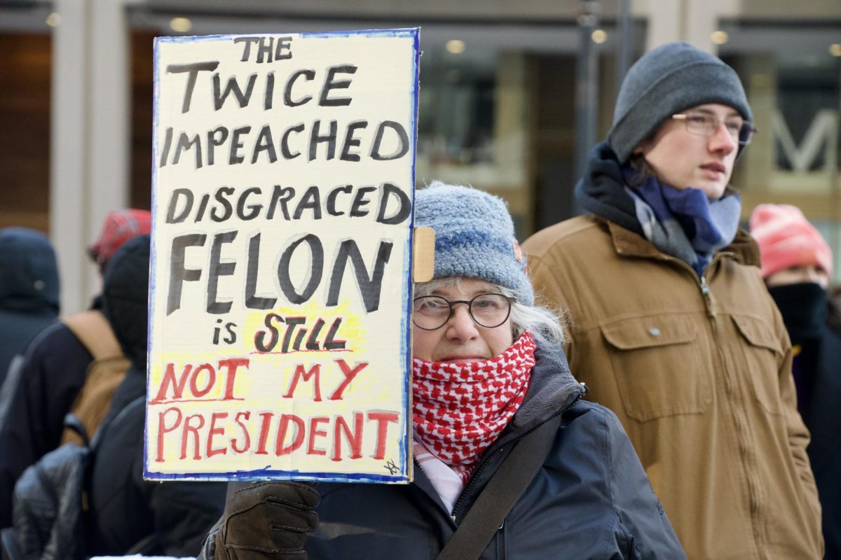 A woman holds up a sign at the We Fight Back rally. Her sign referenced Trump’s two previous impeachments and 34 felony counts.