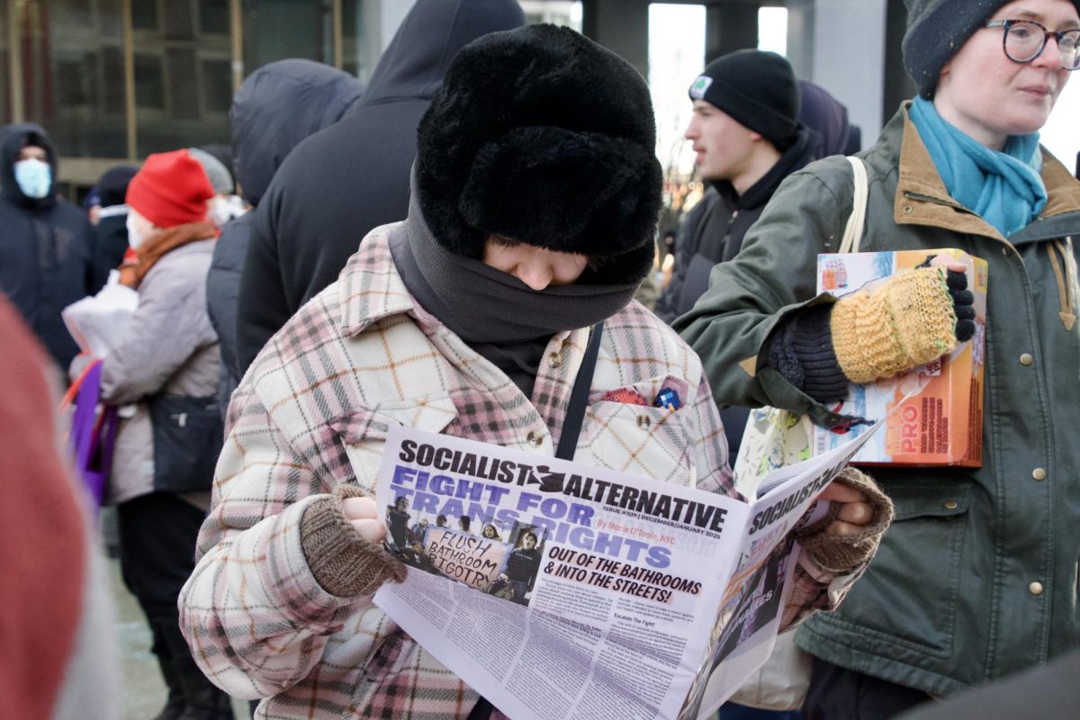 A protester reads a newspaper issue by the Socialist Alternative, an organization dedicated to the movement toward a democratic and socialist society. Outside the John F. Kennedy Federal Building were tables that displayed free editorial and opinion newspapers.