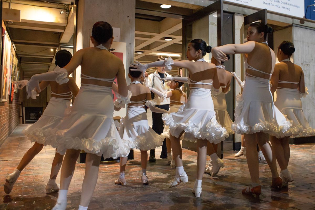 A troupe of young girls in white costumes rehearse their dance routine. Among the group were Liu’s two daughters. 