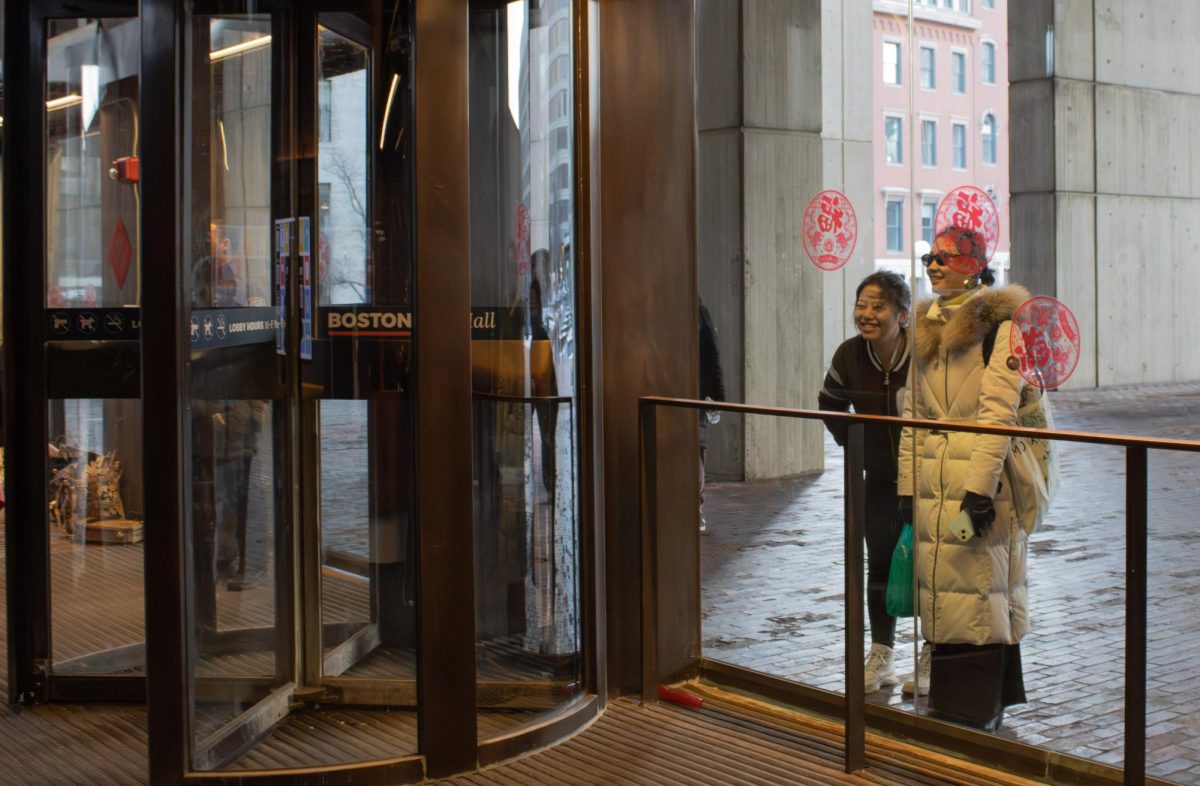 Two women smile as they watch the gala’s performances through City Hall’s glass panels. Although the festival’s location has not changed since last year, a large turnout drove the building to maximum capacity. 