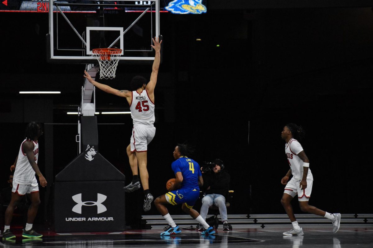 Collin Metcalf leaps to try to block Delaware’s Niels Lane. Metcalf collected his season high in points at nine Jan. 2.