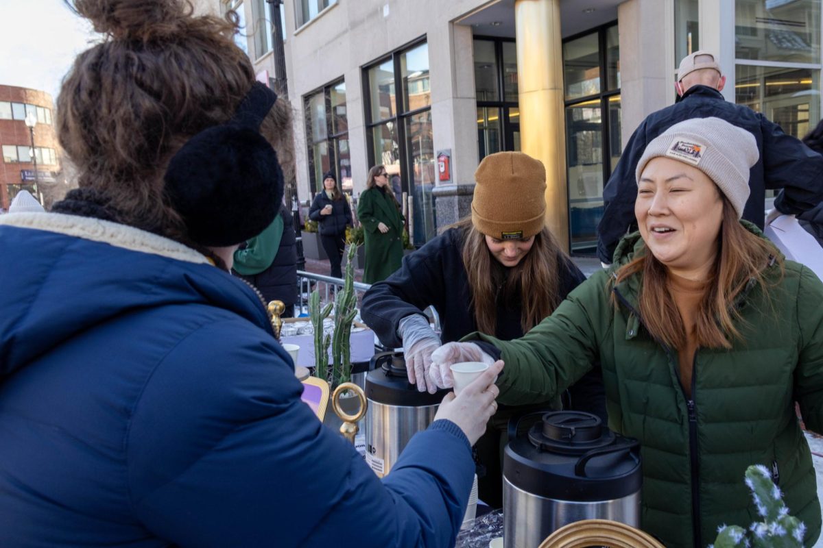 A vendor hands over a sample cup of hot chocolate. Many people happily anticipated the three kinds of hot chocolate offered in the cold weather.